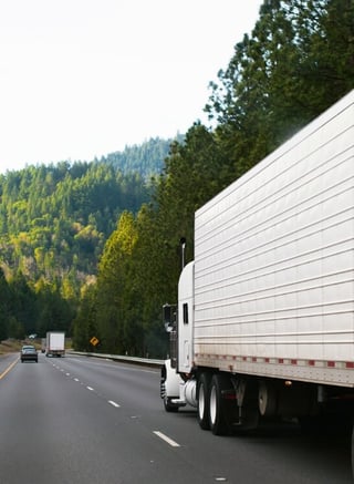 White semi driving in forest - commercial auto liability 