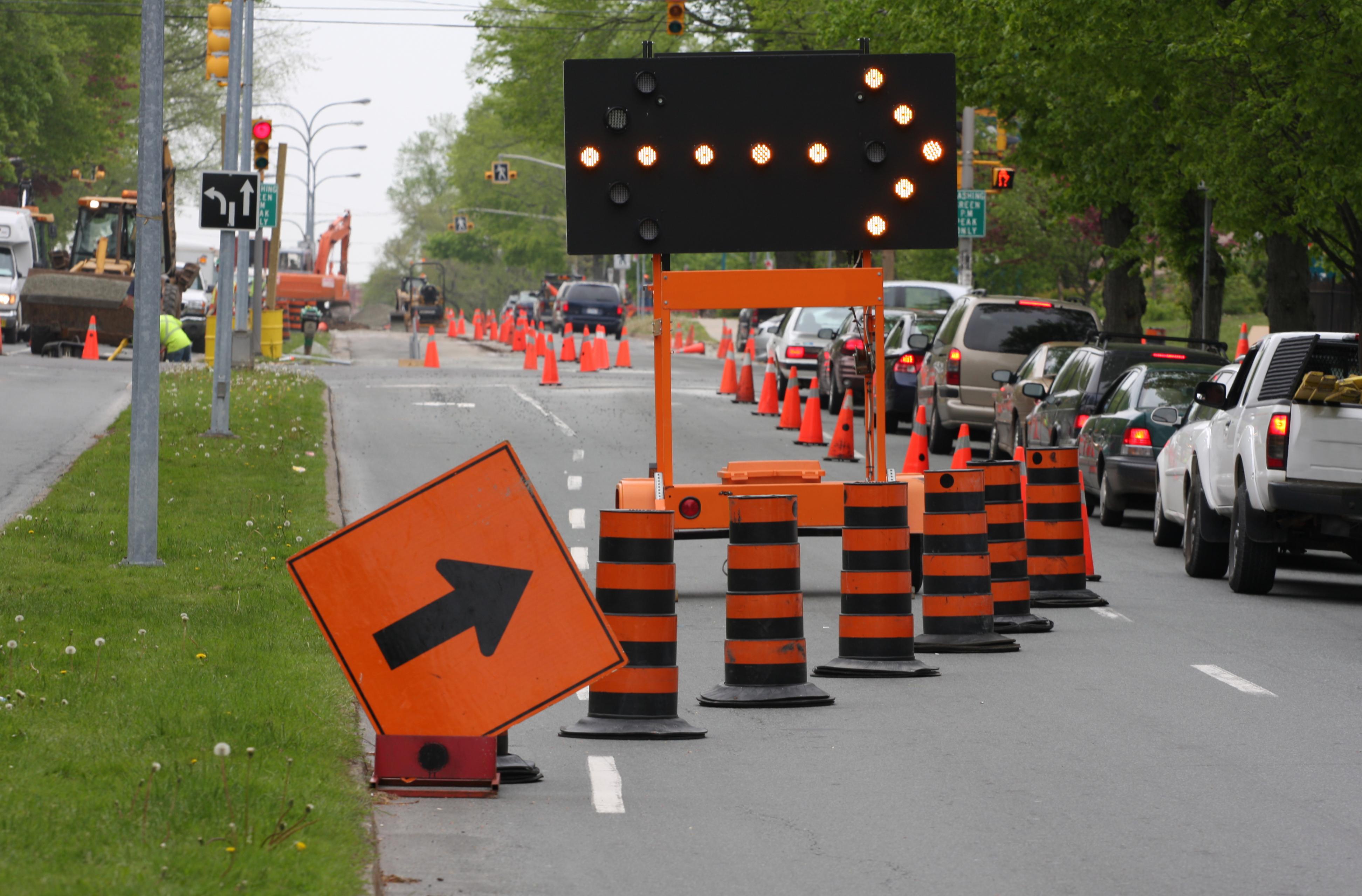 road construction signs and cones beside traffic 
